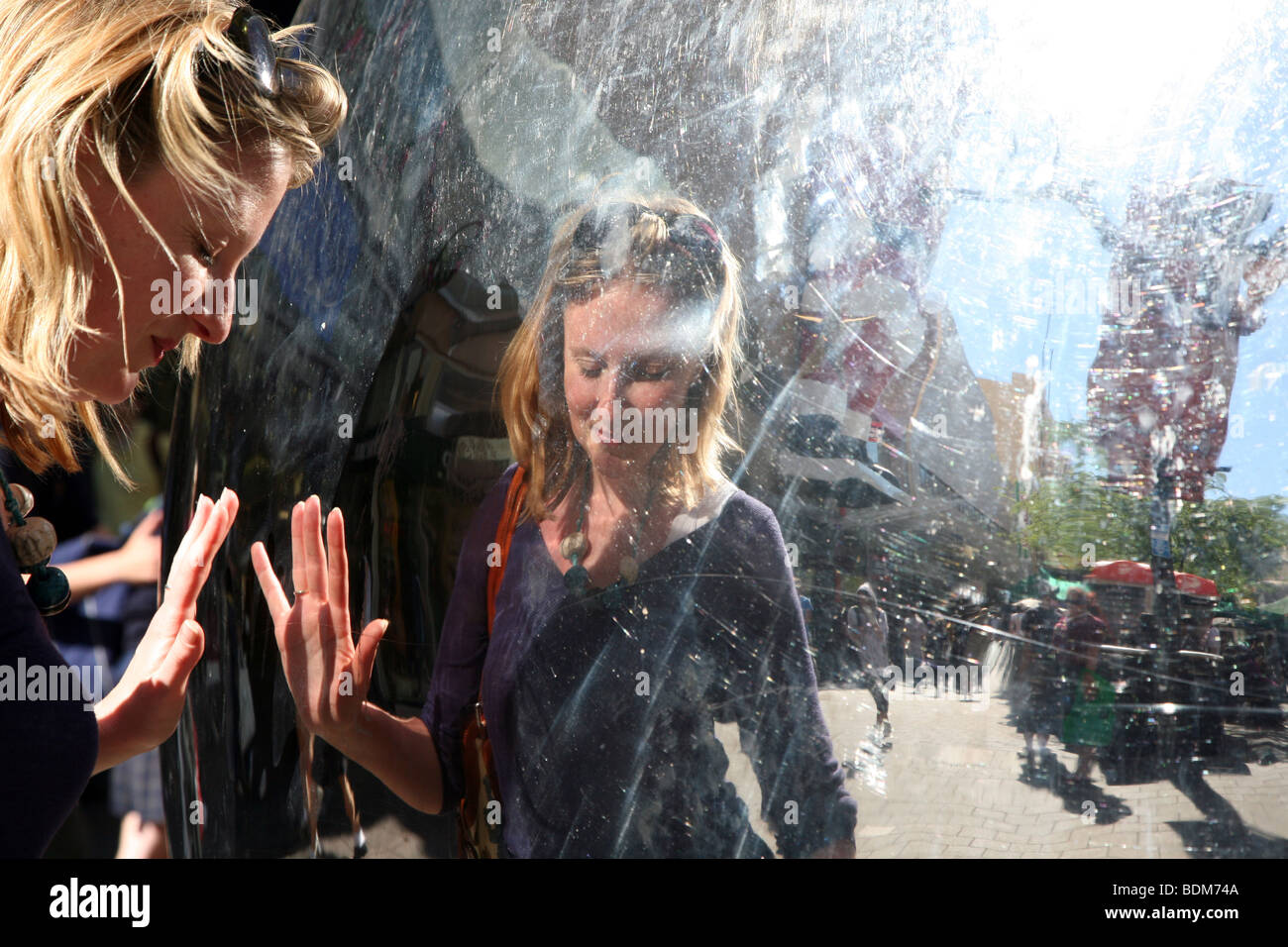 Frau schaut ihr Spiegelbild in "The Malls Balls", Rundle Mall, Adelaide. Die Bereichen Skulptur von Bert Flugleman. Stockfoto