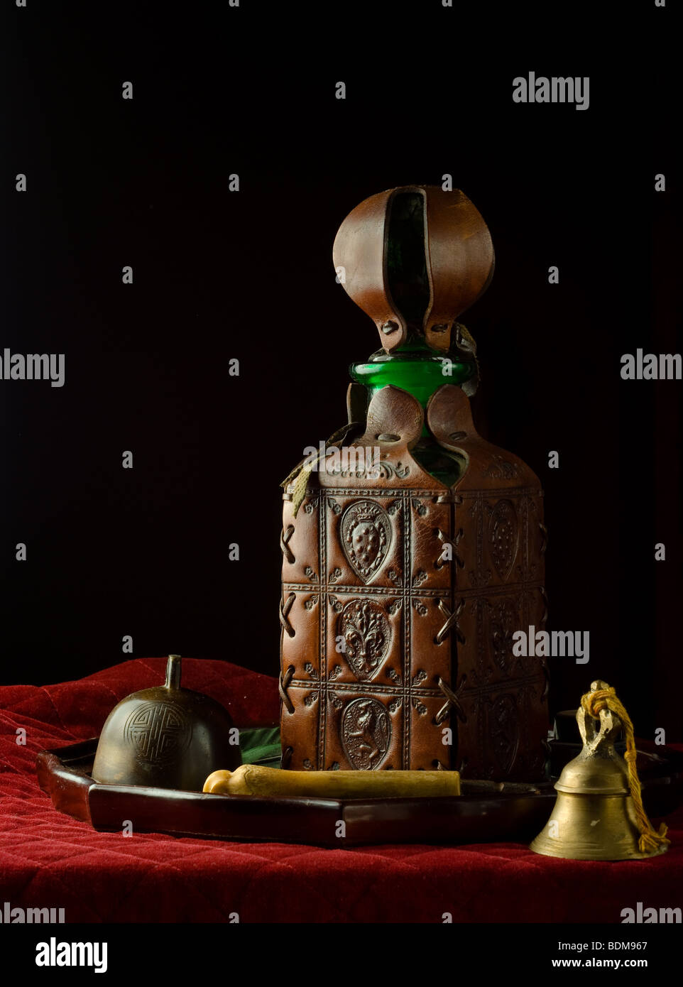 Stillleben mit Tablett mit Leder bezogen-Flasche, Jak Bell, Kuhglocke, Knochen behandelt Gabel auf dicken Quilt. Stockfoto