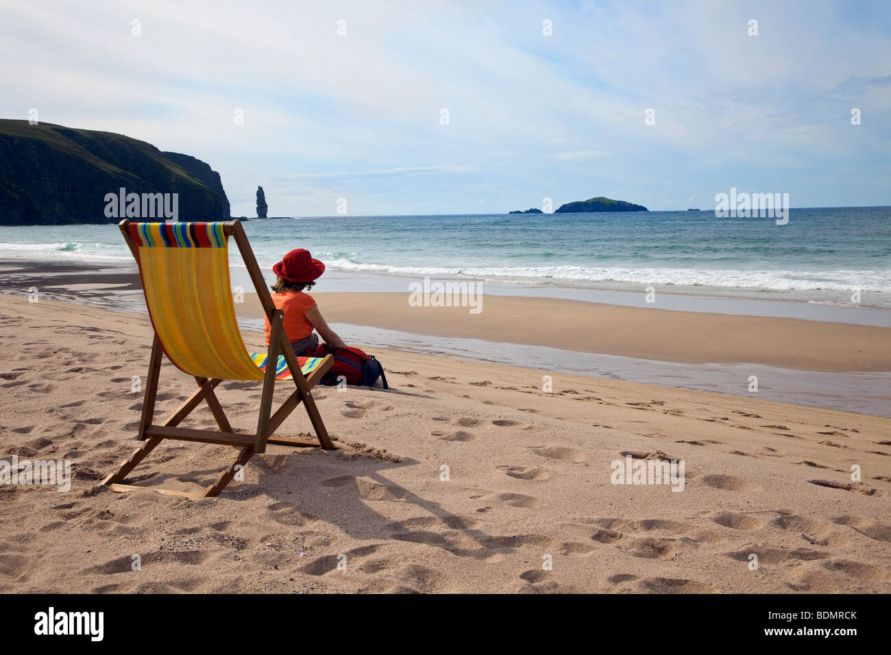 Frau am Strand sitzen auf dem Sand in der Nähe von Liegestuhl Sandwood Bay, Sutherland in den westlichen Highlands von Schottland, UK Stockfoto