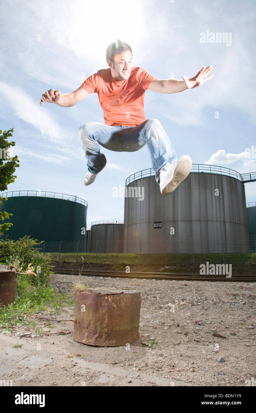 Junger Mann vor einer Industrieanlage zu springen Stockfoto