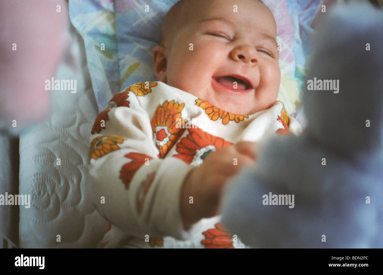 Baby spielt im Gitterbett freudig Lachen an ihrem Spielzeug Stockfoto