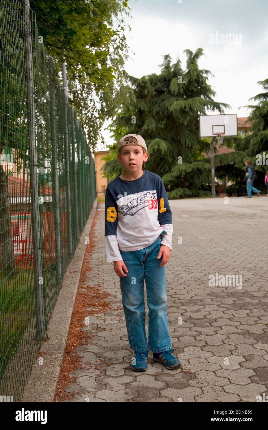 Ricky nach der Schule an einem Frühlingstag, Basketball hoop im Hintergrund, ist es den Schulhof in Armeno, VB, Italien Stockfoto
