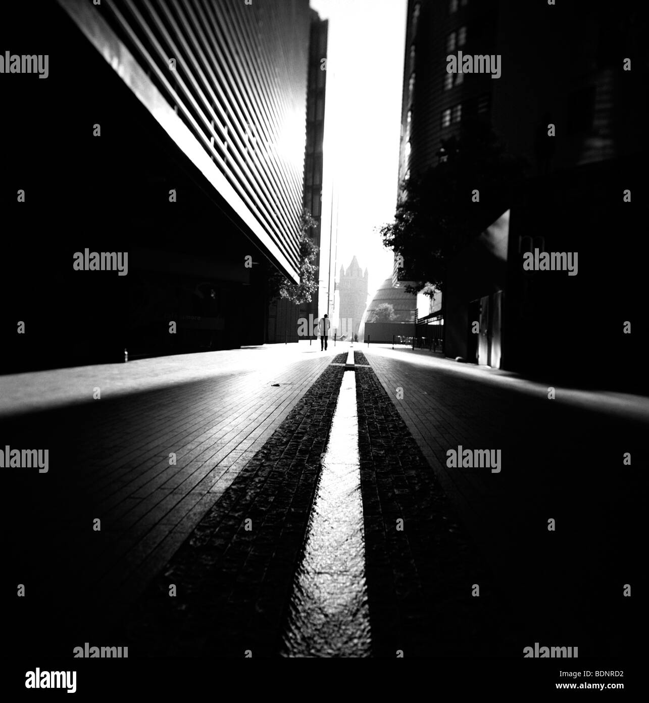 Einsame Gestalt, die dunkle Straße entlang mit hohen Gebäuden London England Stockfoto