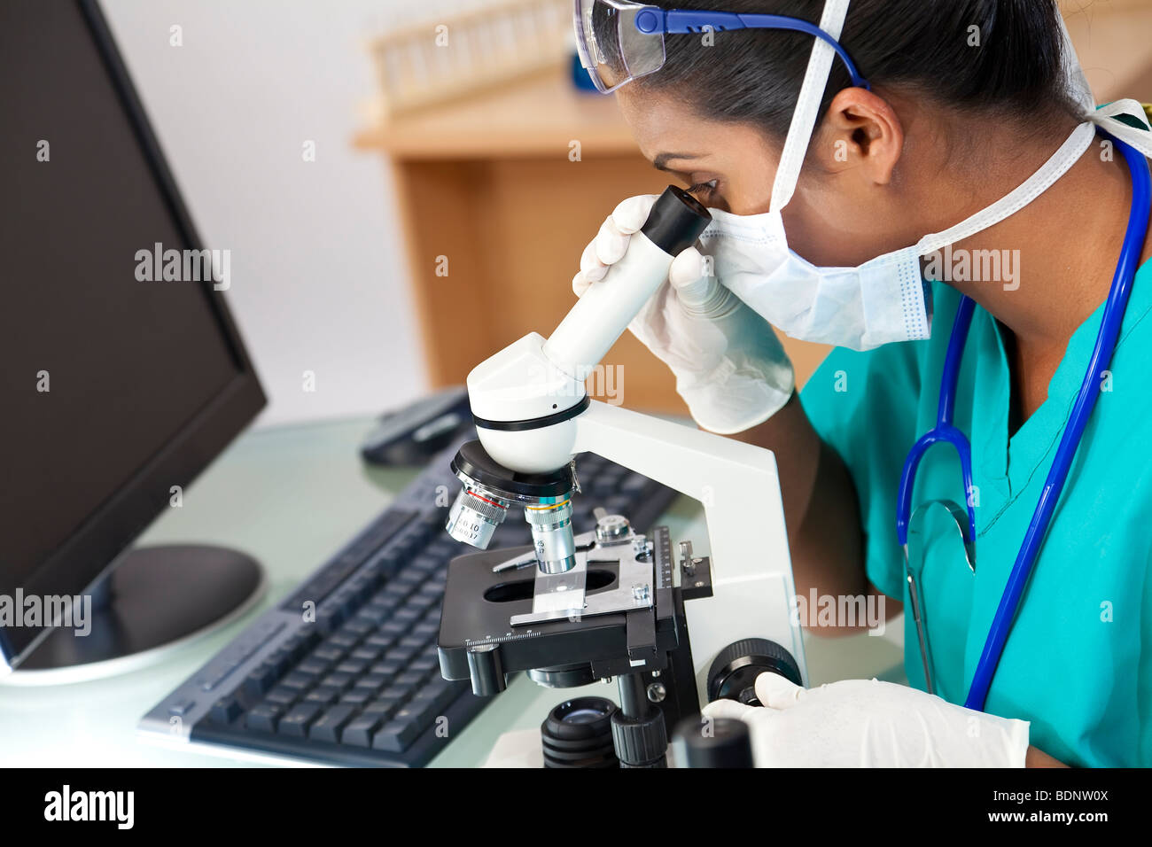 Eine asiatische Frauen Arzt oder wissenschaftlicher Mitarbeiter mit ihrem Mikroskop und Computer in einem Labor. Stockfoto