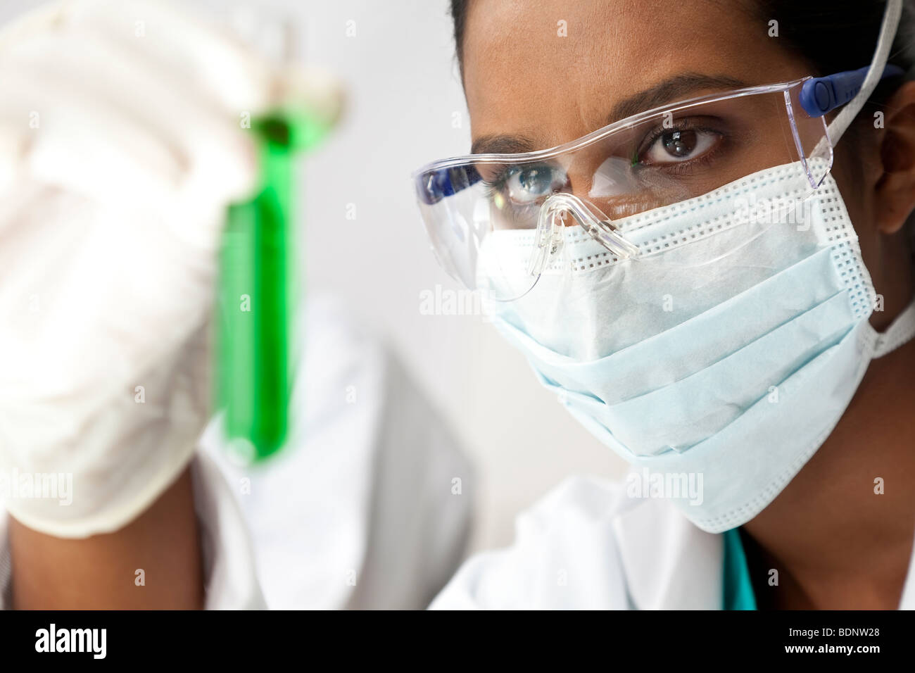 Eine asiatische medizinische oder wissenschaftliche Forscher oder Arzt ein Reagenzglas grüne Lösung in einem Labor zu betrachten. Stockfoto