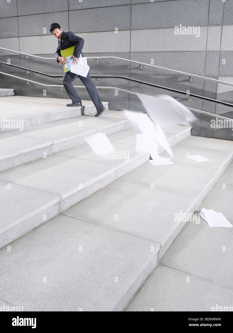 Business-Mann zu Fuß Schritte verlieren Papiere aus der Aktentasche, im Freien, Seitenansicht Stockfoto