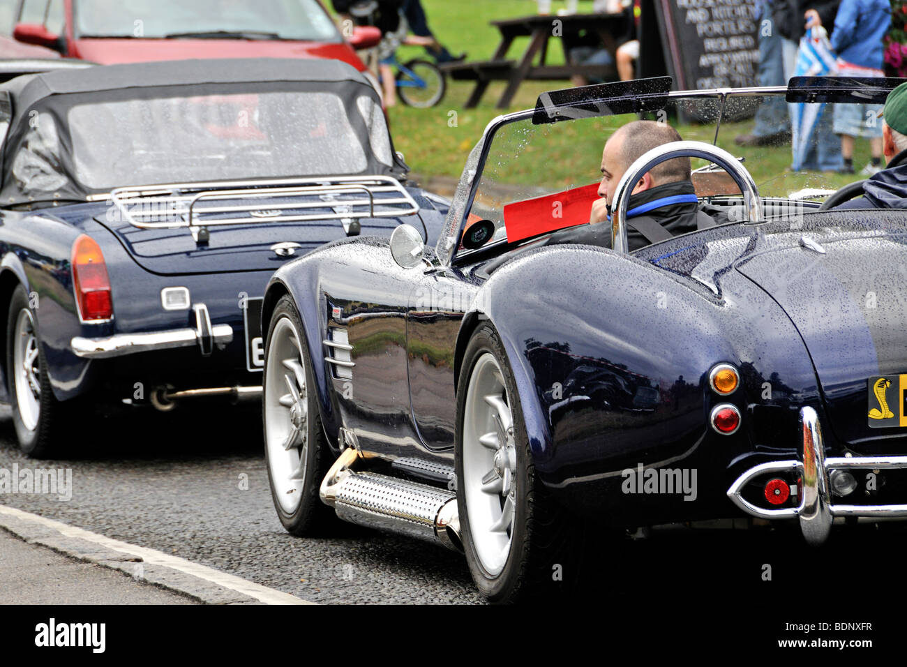 Blaue AC Cobra Oldtimer auf der Straße & im Verkehr mit anderen Oldtimern. Stockfoto