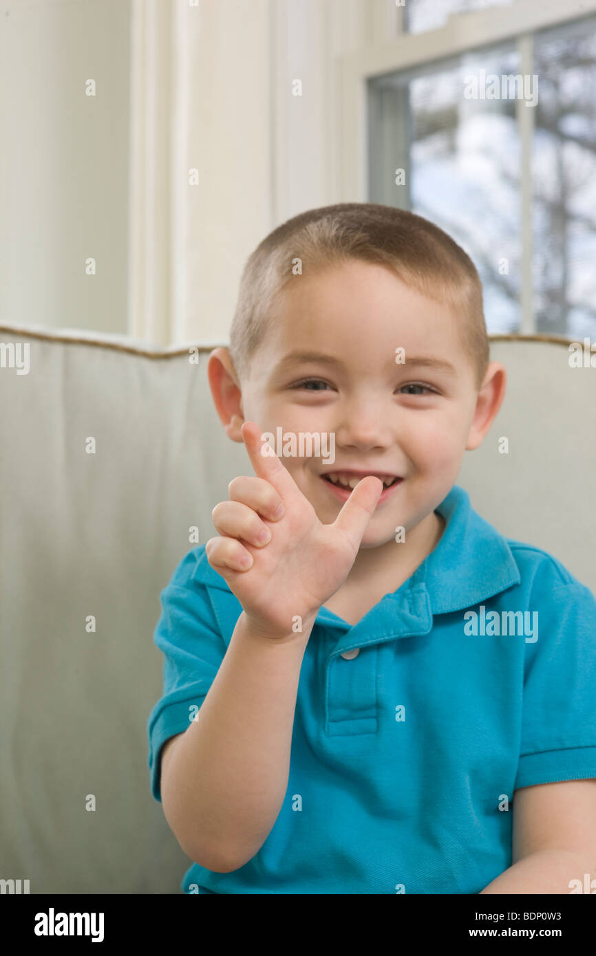 Junge, die Unterzeichnung der Buchstabe "L" in amerikanischer Gebärdensprache Stockfoto