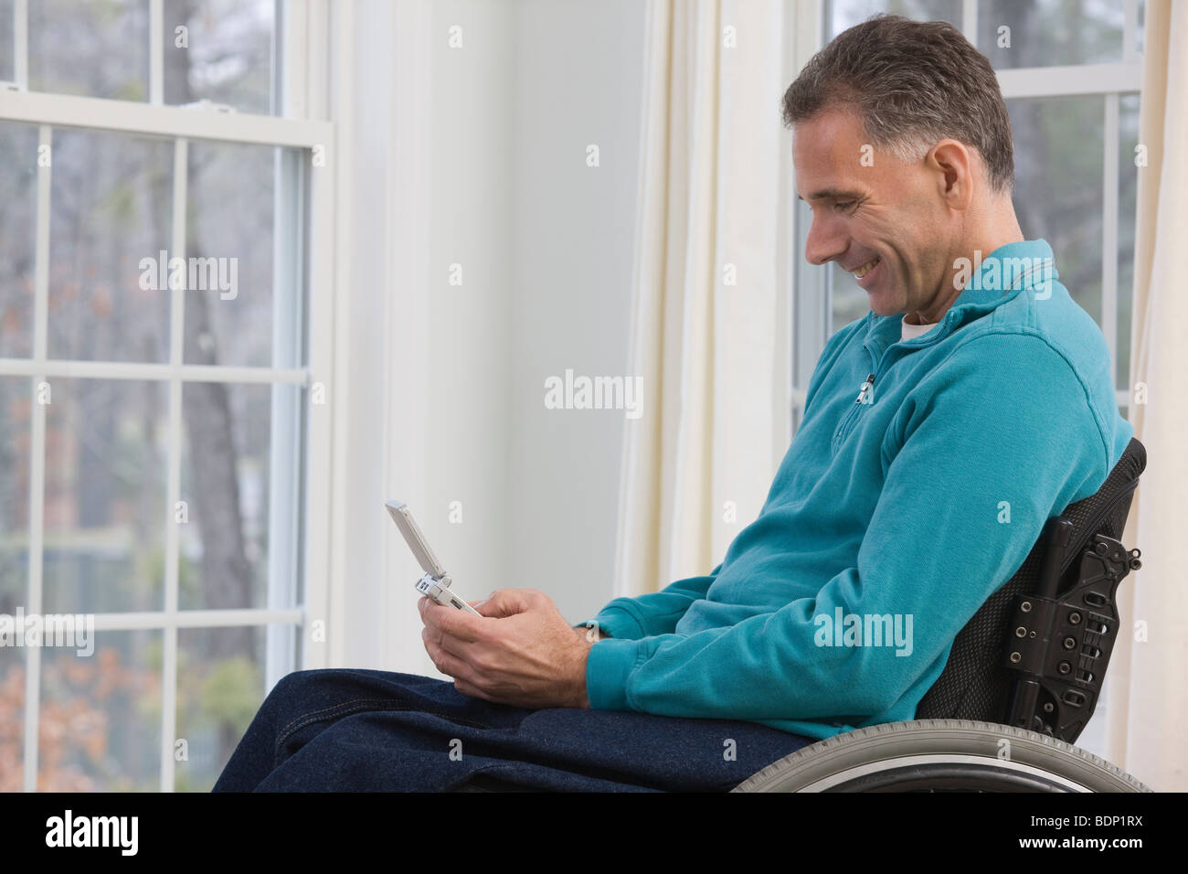 Mann in einem Rollstuhl sitzt und verwenden personenbezogene Daten-Assistenten Stockfoto