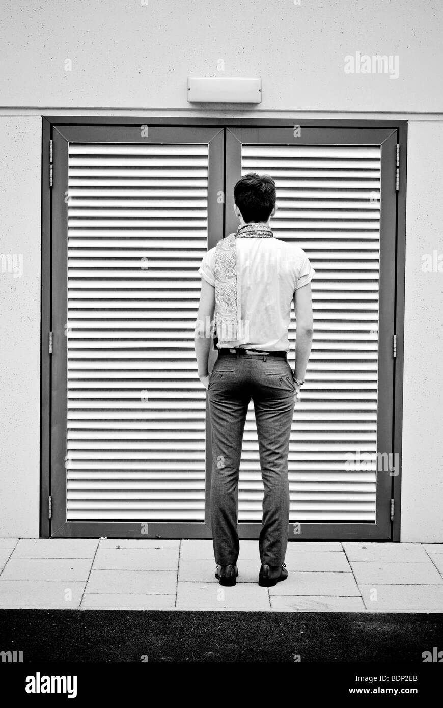 Ein junger Mann mit Blick auf einen Lattenrost Eingang auf der Straße Stockfoto