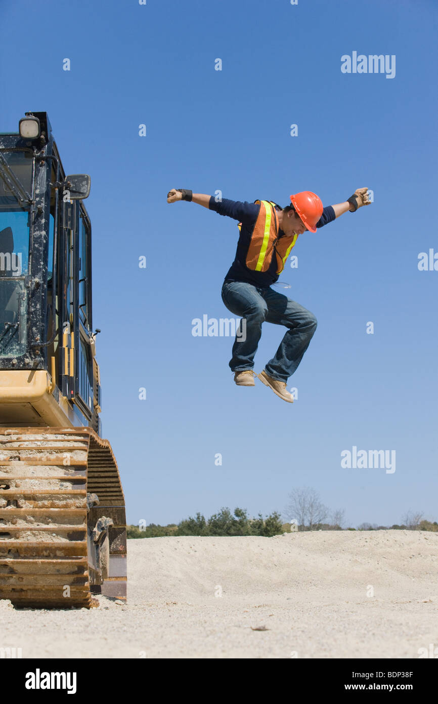 Ingenieur aus einem Bagger herausspringende Stockfoto