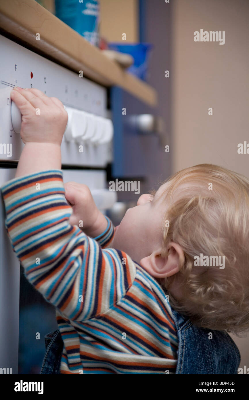 Kleiner Junge die Schalter auf einem elektrischen Ofen erkunden Stockfoto