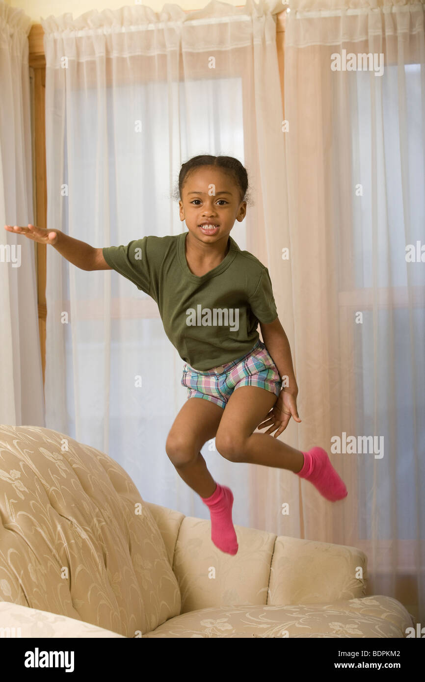 Hispanischen Mädchen auf einer Couch springen Stockfoto