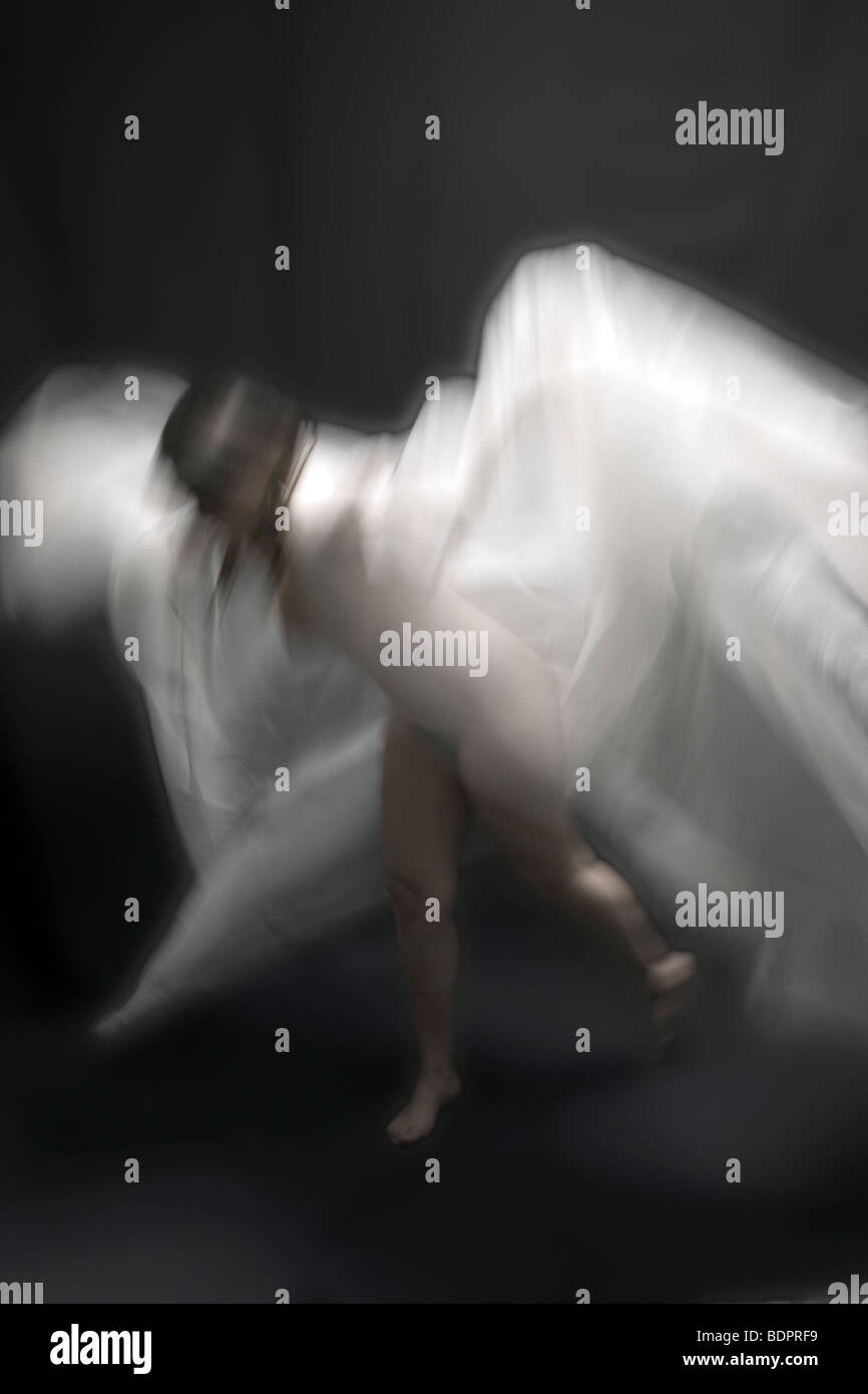 Eine junge Frau bewegt sich in einem weißen Schleier Stockfoto