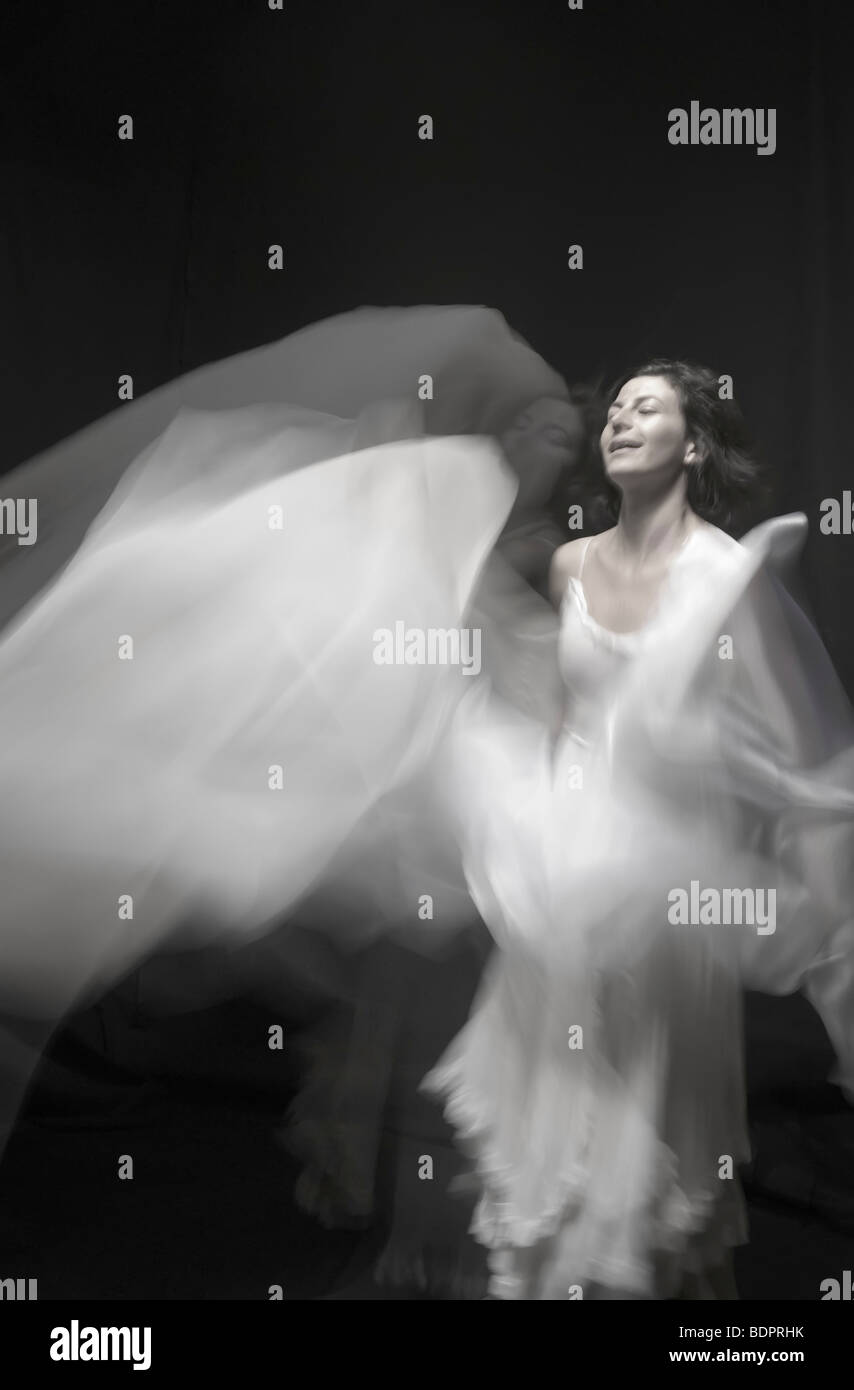 Eine junge Frau in einem weißen Kleid mit einem weißen Schleier in einer Unschärfe tanzen Stockfoto