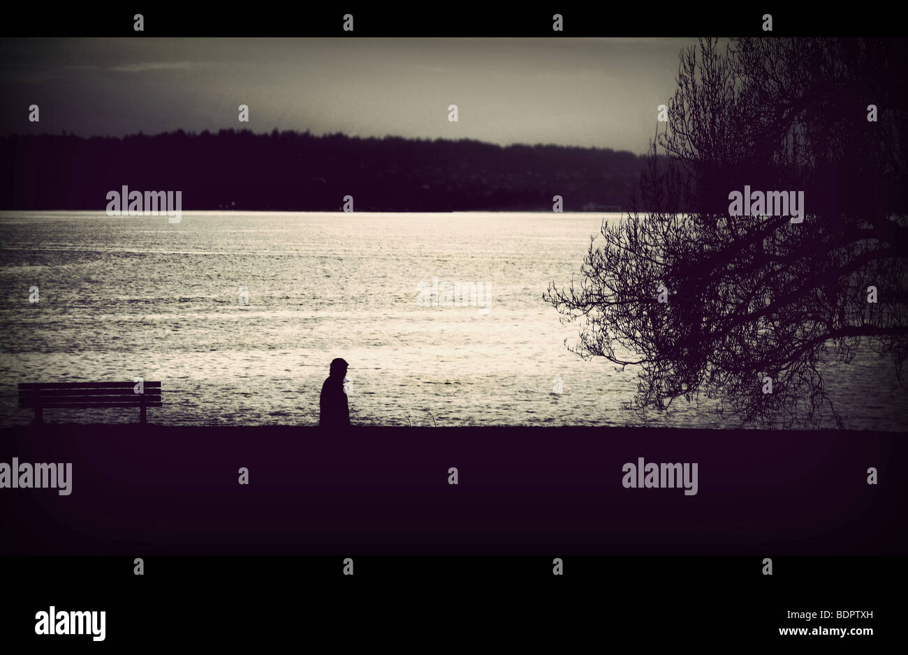 Eine einsame Gestalt zu Fuß neben eine große Wasserfläche Stockfoto