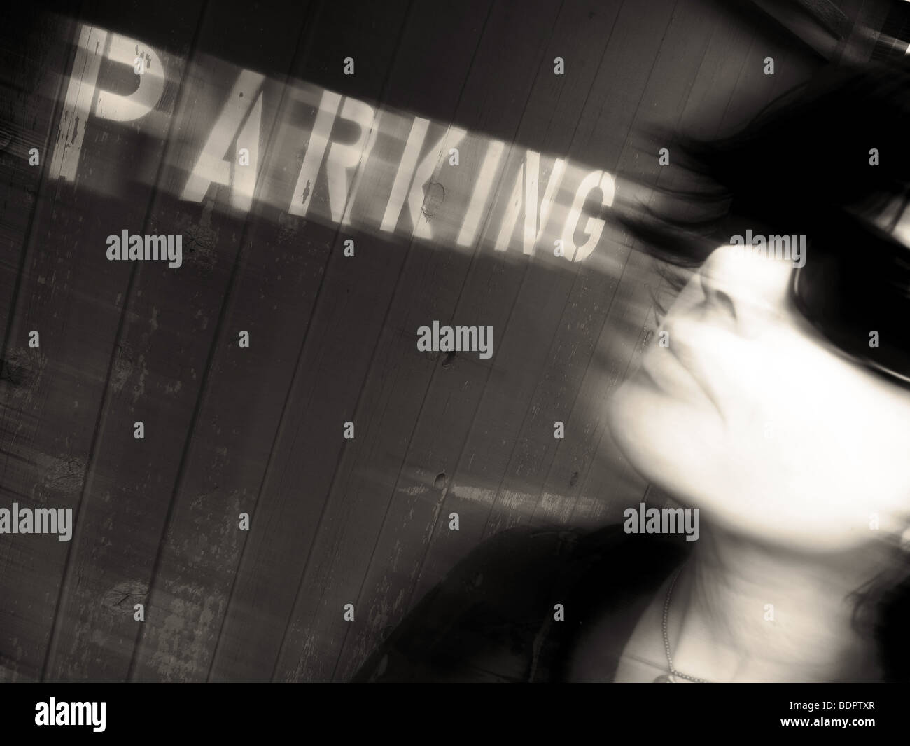 Das Gesicht einer jungen Frau mit coolen dunkler Brille zu Fuß ging ein Parkplatz-Schild Stockfoto