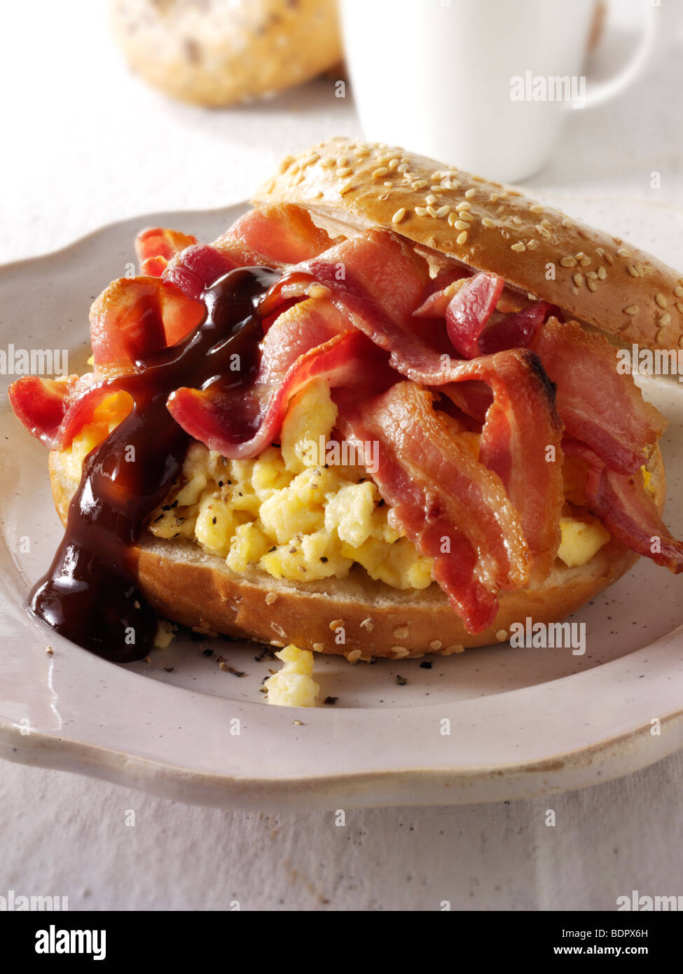 Knusprigem Speck und Rührei auf einen Bagel mit brauner Soße Stockfoto