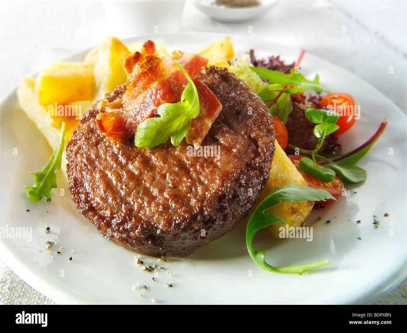 Char, gegrilltes Rindfleischburger und Speck mit klobigen Pommes Frites und Salat Stockfoto