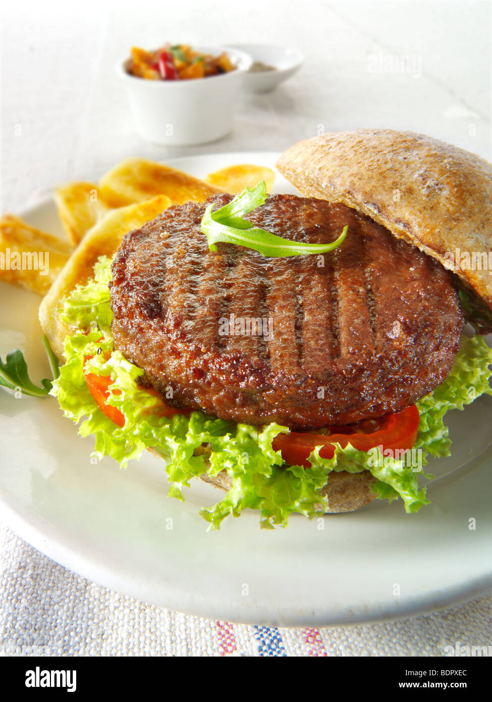 Beef-Burger in einem Vollkorn Brötchen mit Salat und Pommes frites Stockfoto