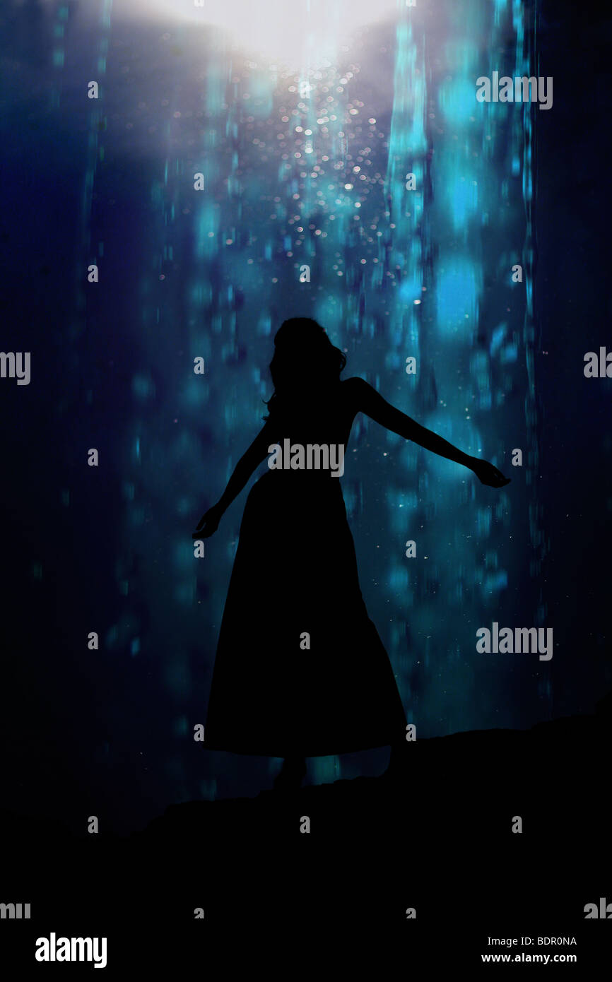 Die Silhouette einer jungen Frau tanzen vor einem blauen Hintergrund Stockfoto