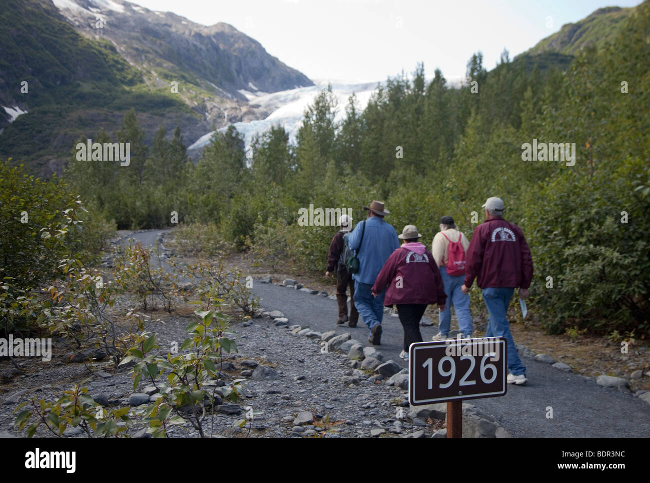 Besucher zu Fuß, vorbei an einem Schild unter Exit-Gletscher in Kenai Fjords Nationalpark zeigt, wie weit den Gletscher im Jahr 1926 erweitert Stockfoto