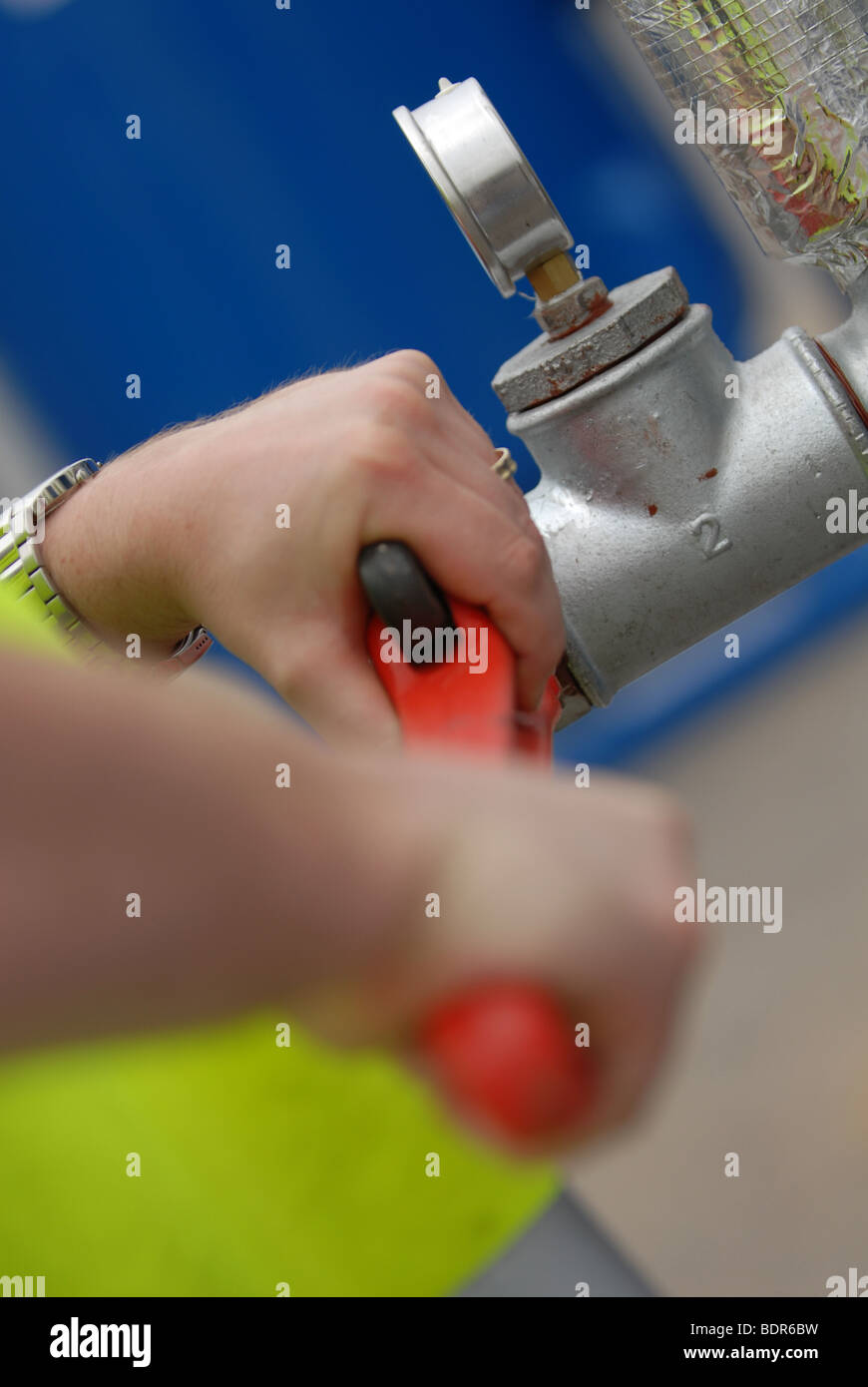 Arbeiter halten einen großen Schraubenschlüssel Schraubenschlüssel und ein Wasserventil einschalten Stockfoto