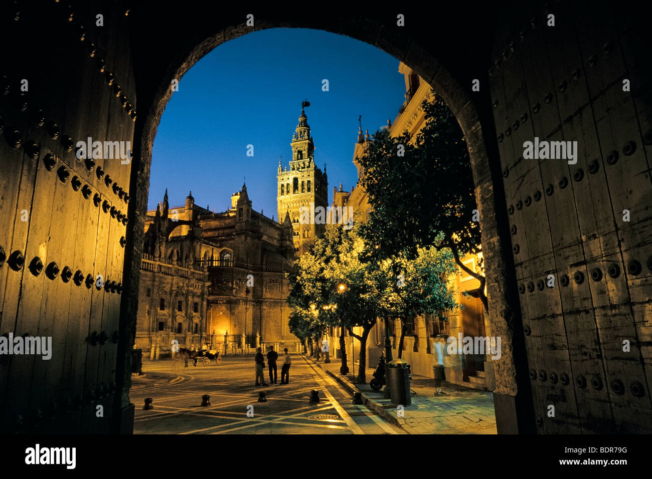 Spanien, Sevilla, Giralda Turm mit dem Dom auf der linken Seite in der Dämmerung durch die Wände des Alcazar angesehen Stockfoto