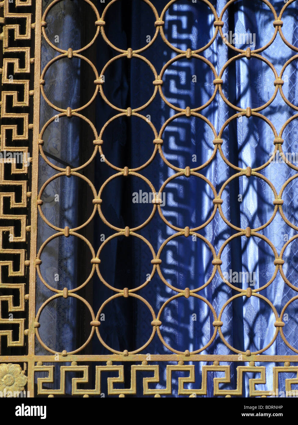 Detail der blaue Vorhänge am Fenster mit rostigem Metall grill Stockfoto