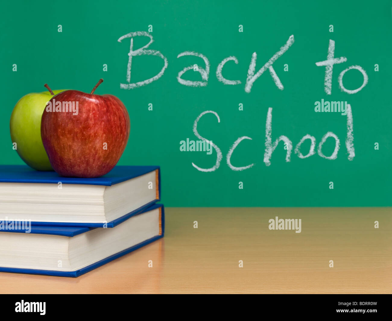 Zurück in der Schule auf eine Tafel geschrieben. Zwei Äpfel über Bücher im Vordergrund. Stockfoto