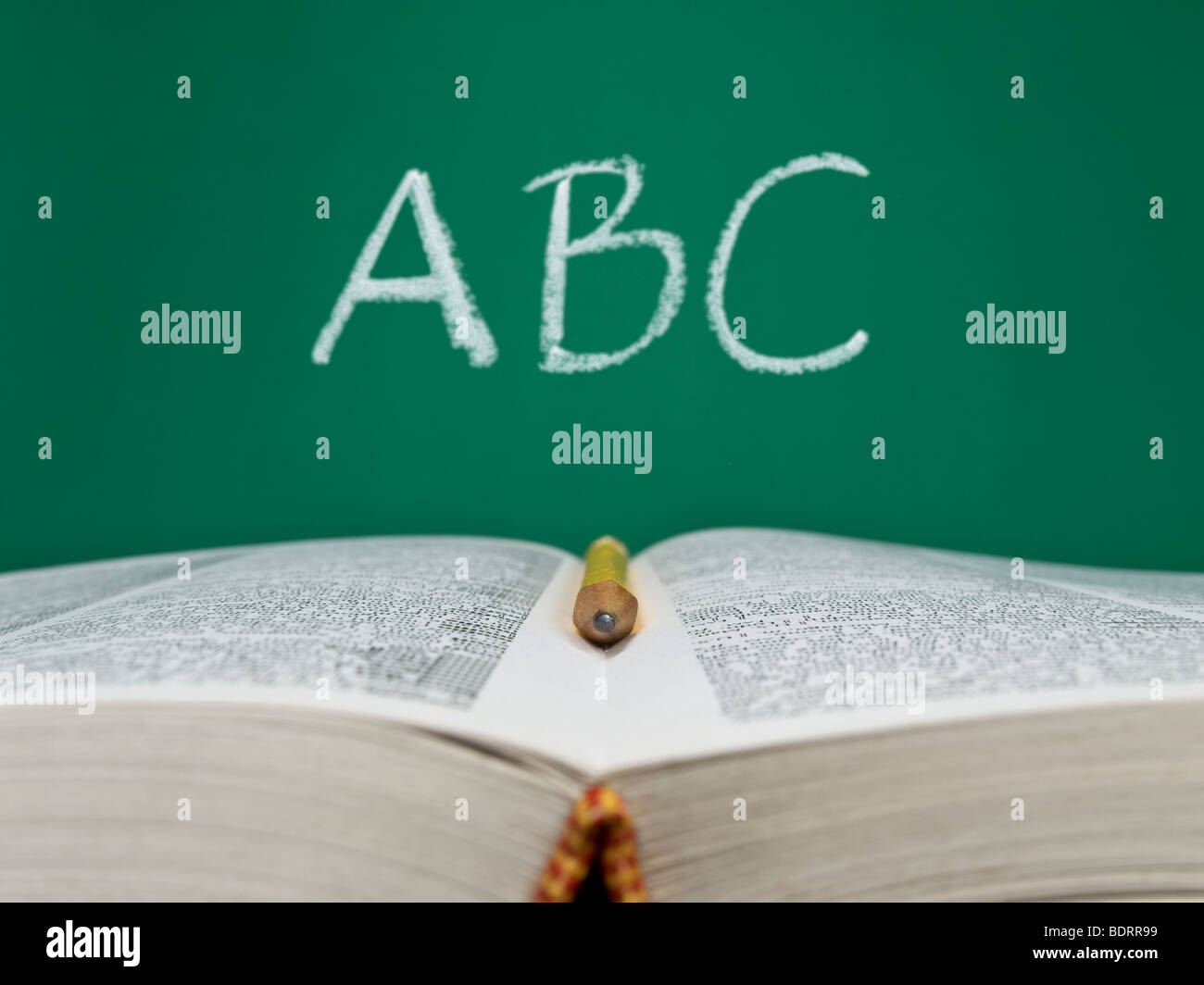 ABC auf einer Tafel mit Stift im Vordergrund und ein offenes Buch geschrieben. Stockfoto