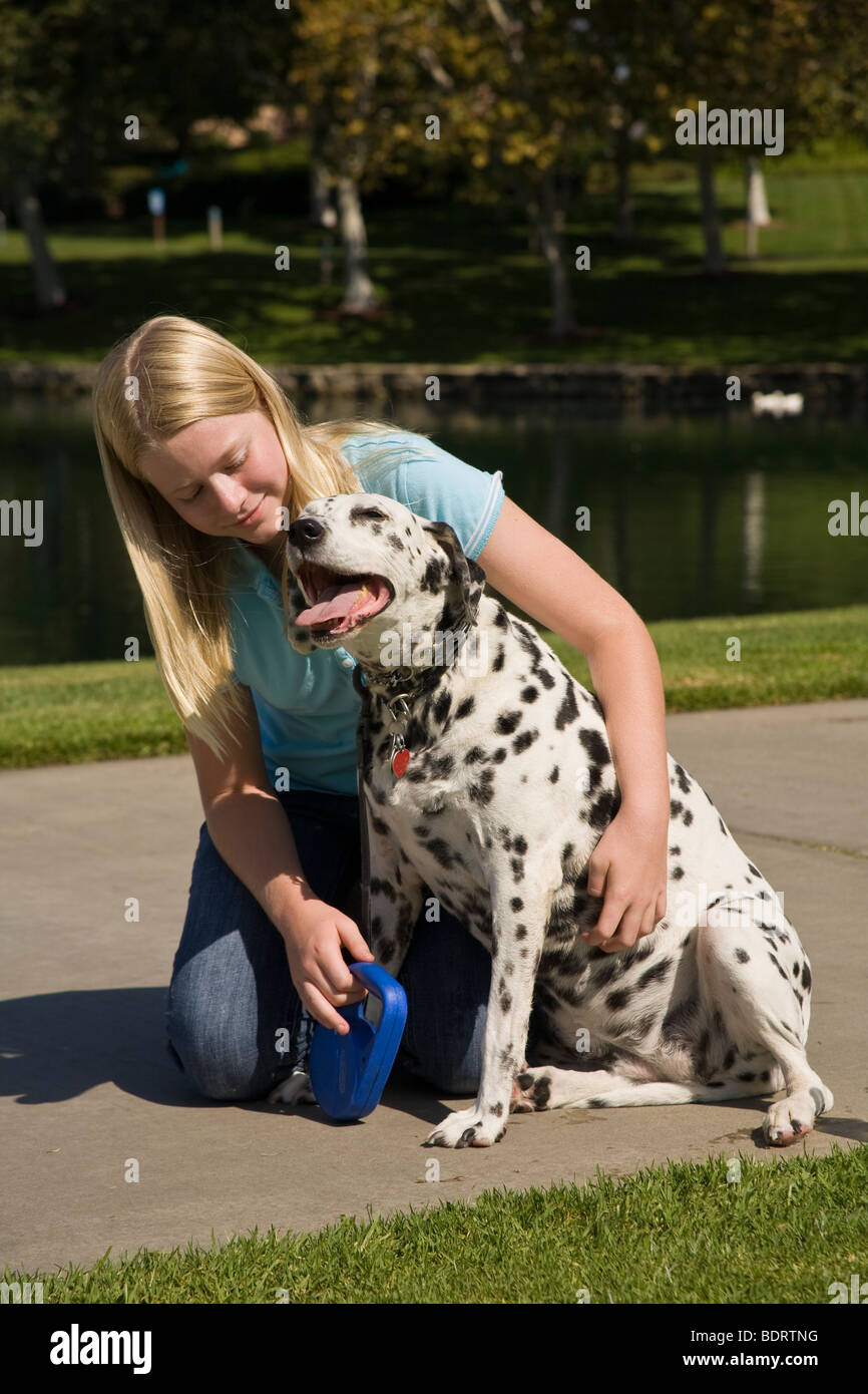 Kind umarmen Hund 11-13 Jahre alten Arm um Umarmen umarmen Dalmatinischen Hundebesitzer Zuneigung Vorderseite Profil ansehen HERR © Myrleen Pearson Stockfoto