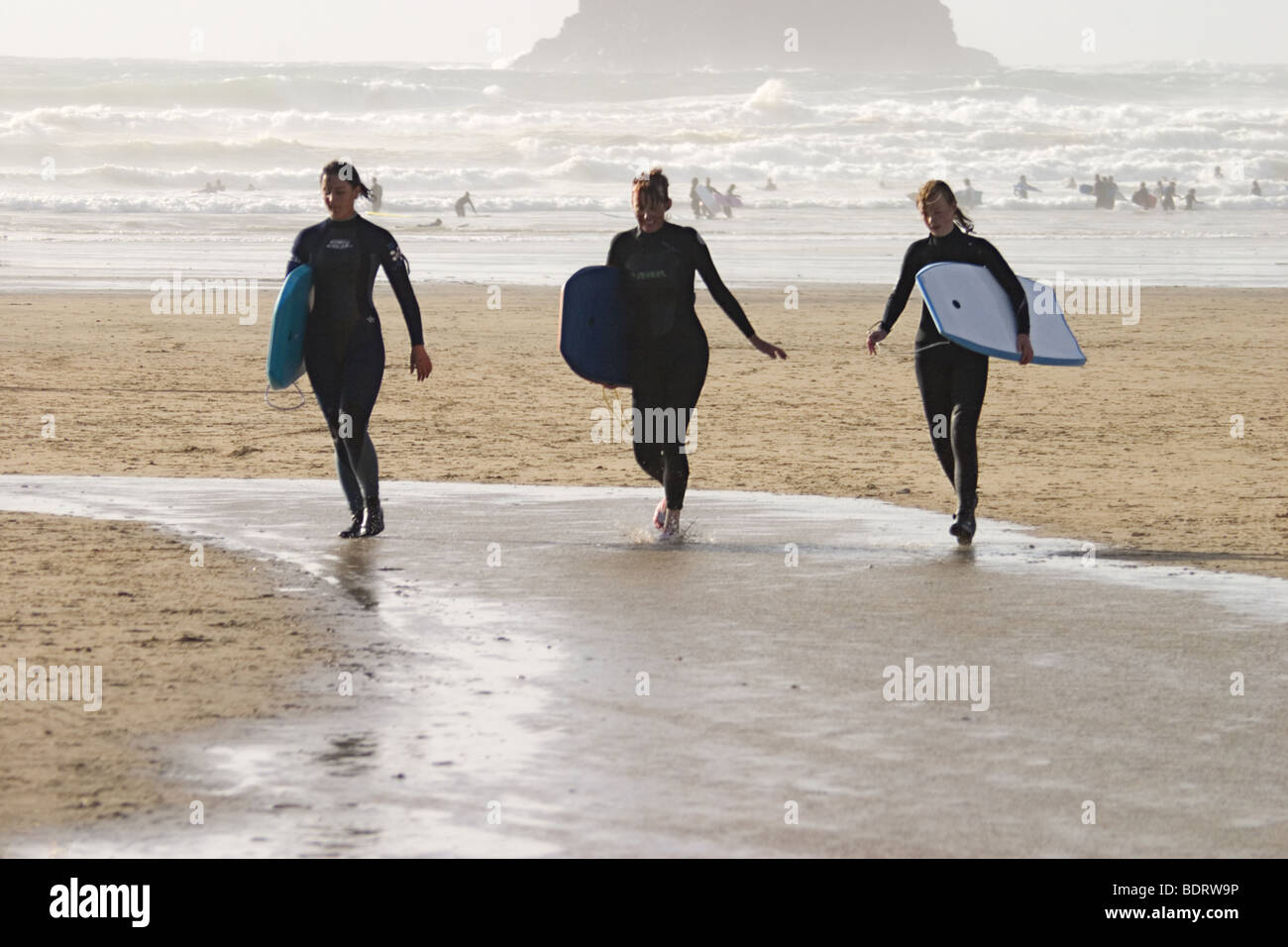 Drei junge Frauen mit Bodyboards, Polzeath Strand, Cornwall Stockfoto