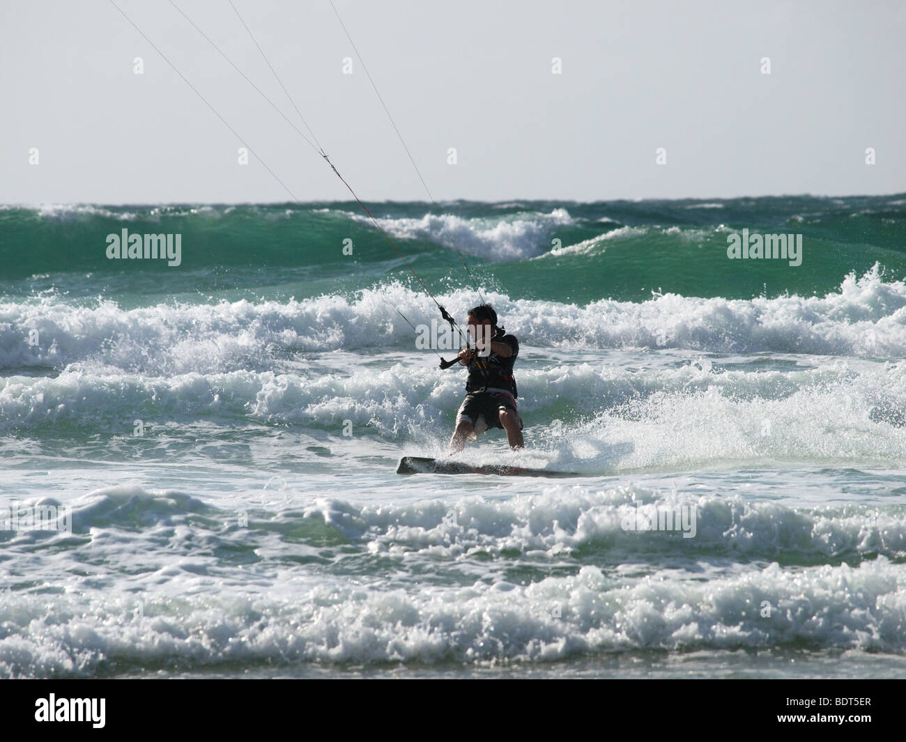 Kitesurfer beschleunigt durch die Wellen bei Les Pieux, Normandie, Frankreich Stockfoto