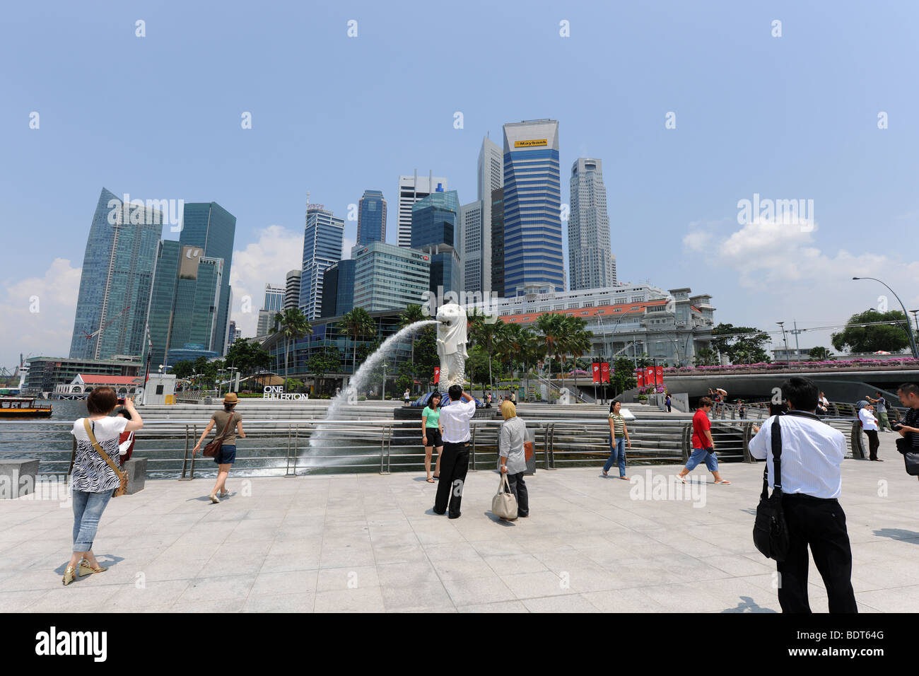 Touristen fotografieren vor der Merlion mit Skyline der Stadt hinter Singapur Stockfoto