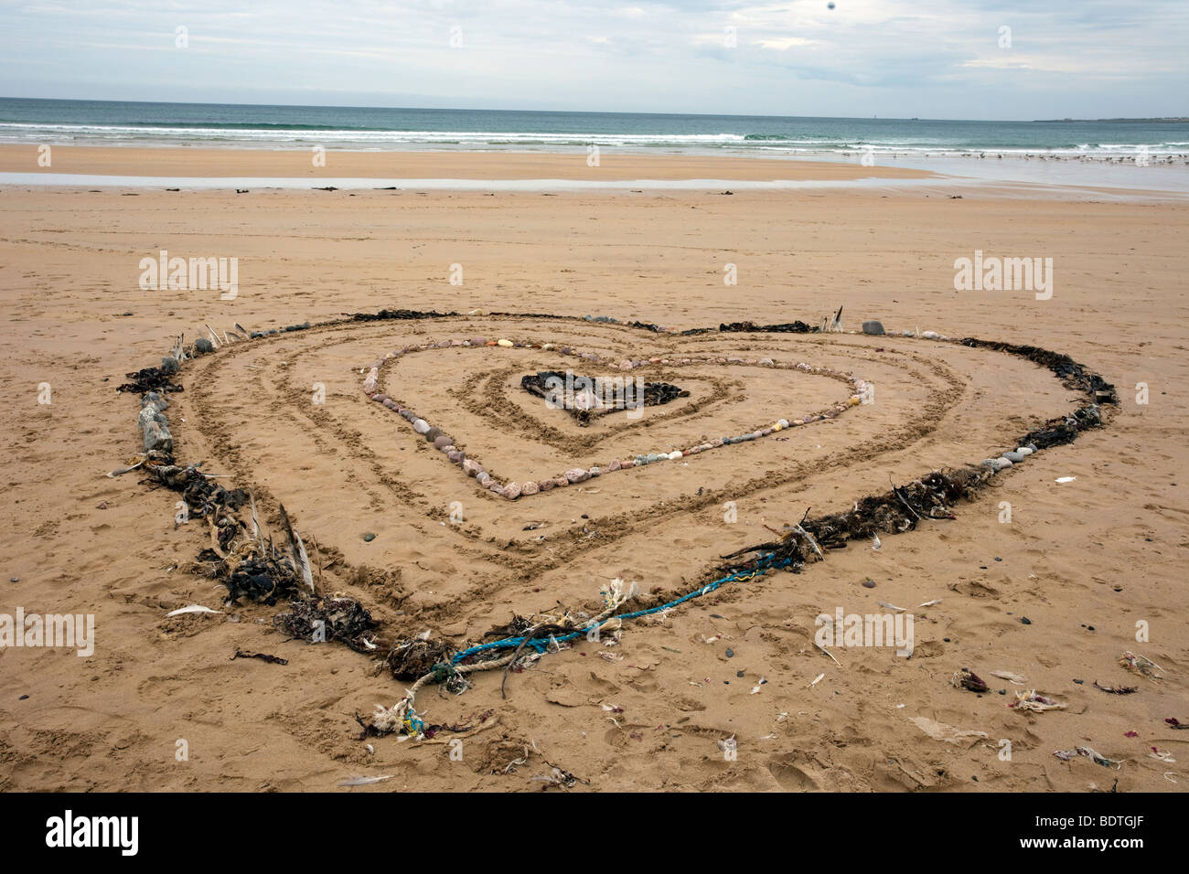 Herzförmiges Muster aus Algen und Steinen; Strandkunst und Sanddünen Küstenlandschaft in Fraserburgh Bay, Aberdeenshire, Schottland, Großbritannien. Stockfoto