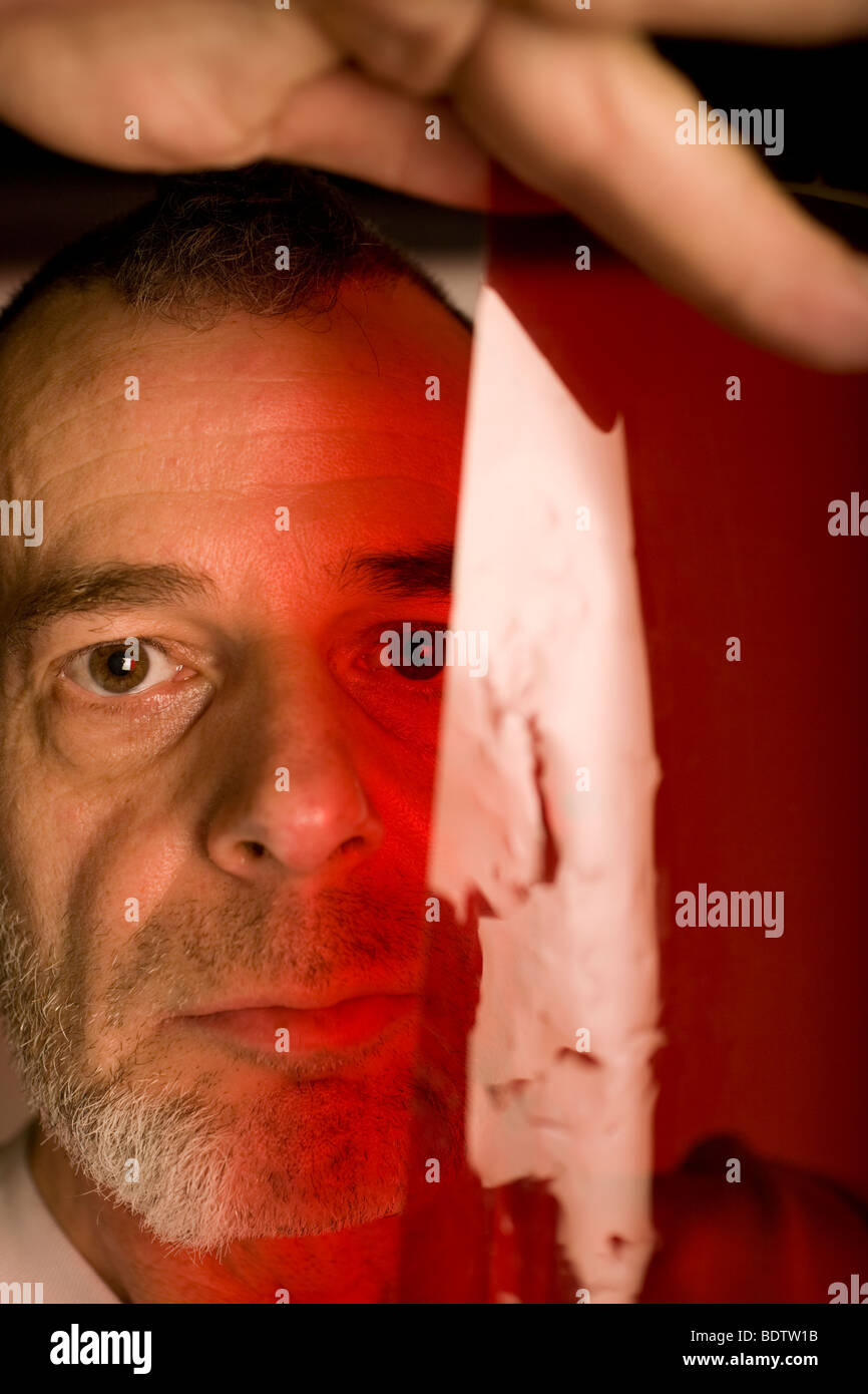 Eine ungewöhnliche, aber künstlerische Bild eines Mannes, der Blick durch ein rotes Gel (Acetat) Blatt. Stockfoto