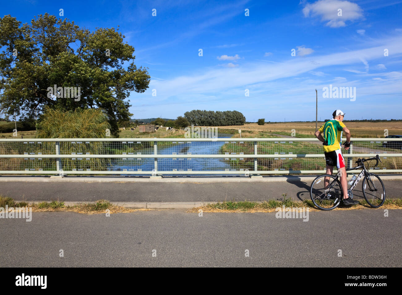Ein älterer Radfahrer ruht auf einer Brücke über die Royal Military Canal auf dem Saxon Shore Weg, in der Nähe von Ruckinge, Kent, Großbritannien Stockfoto