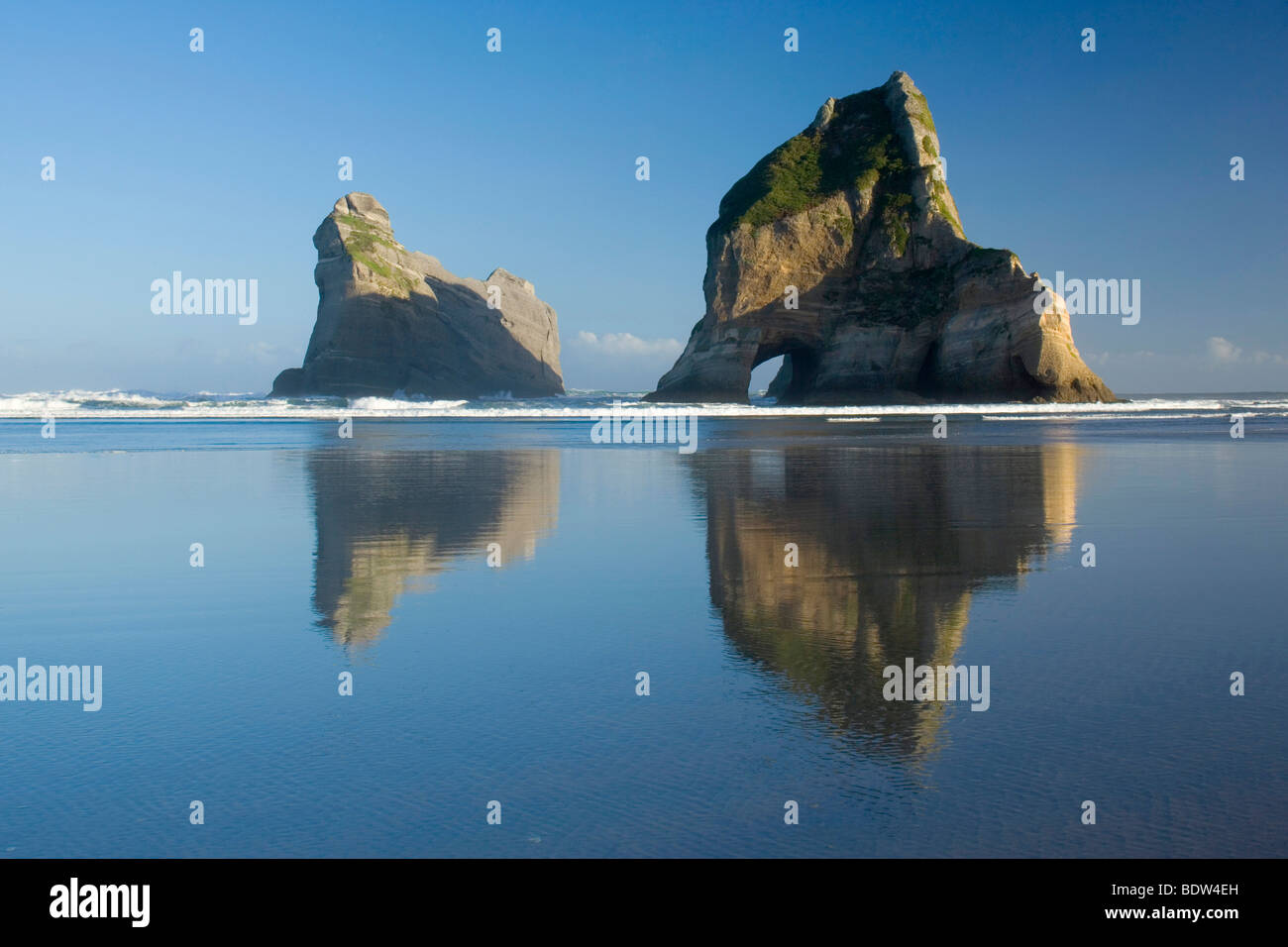 durch die starke Brandung geformte Felsinseln mit Höhlen und Bögen am Wharariki Beach bei Sonnenuntergang, Wharariki Beach, New zealand Stockfoto