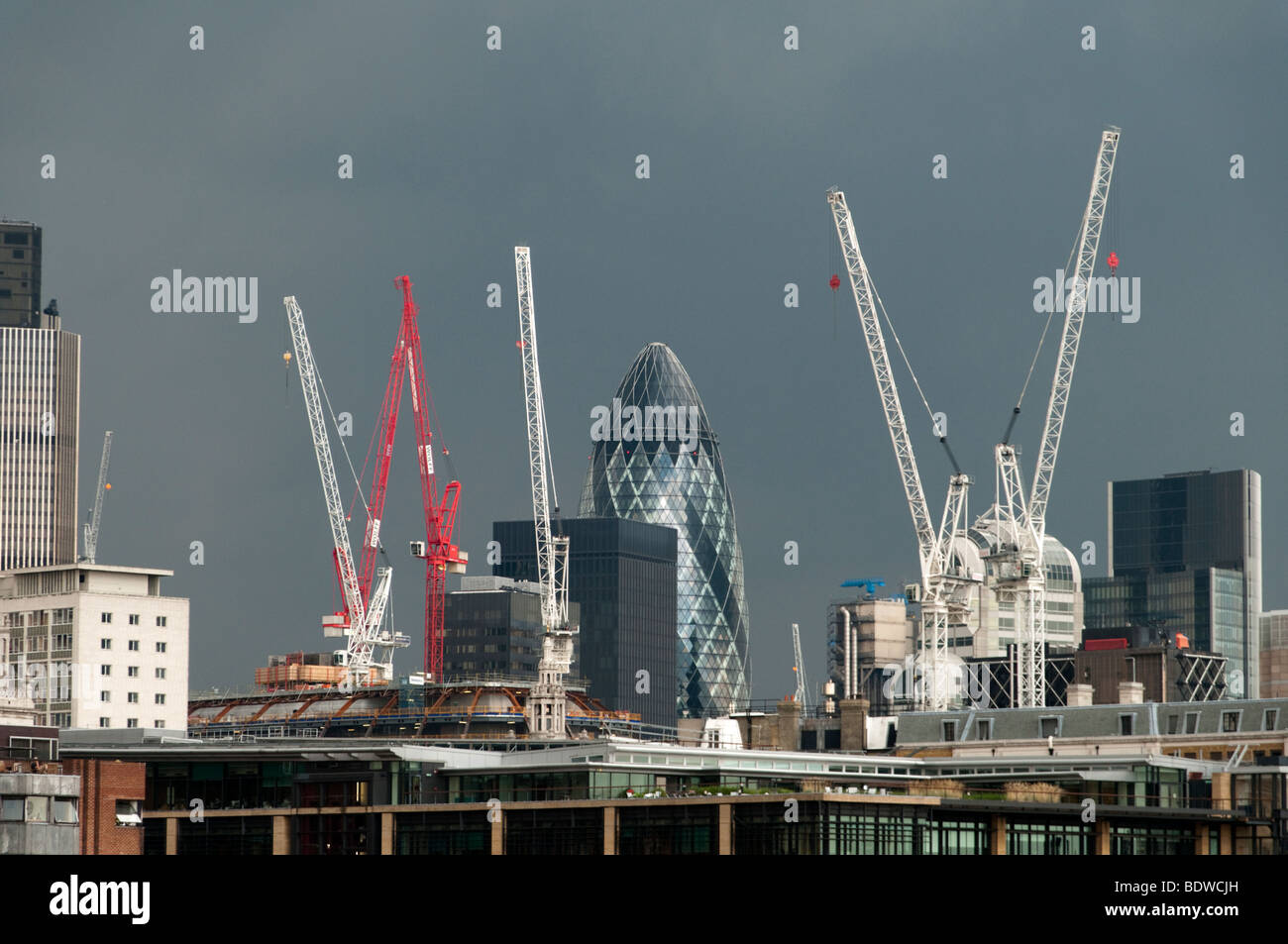 Baukräne in der City of London auf einer dunklen bewölkten Tag, London, England, Großbritannien, UK Stockfoto