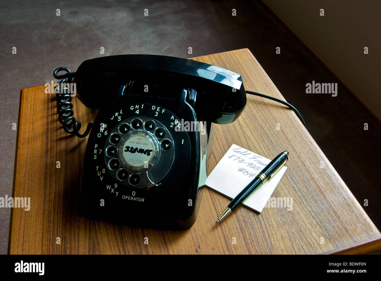 Veraltete Technik alte schwarze Rotary Durchwahltelefon auf Teak Beistelltisch Stockfoto