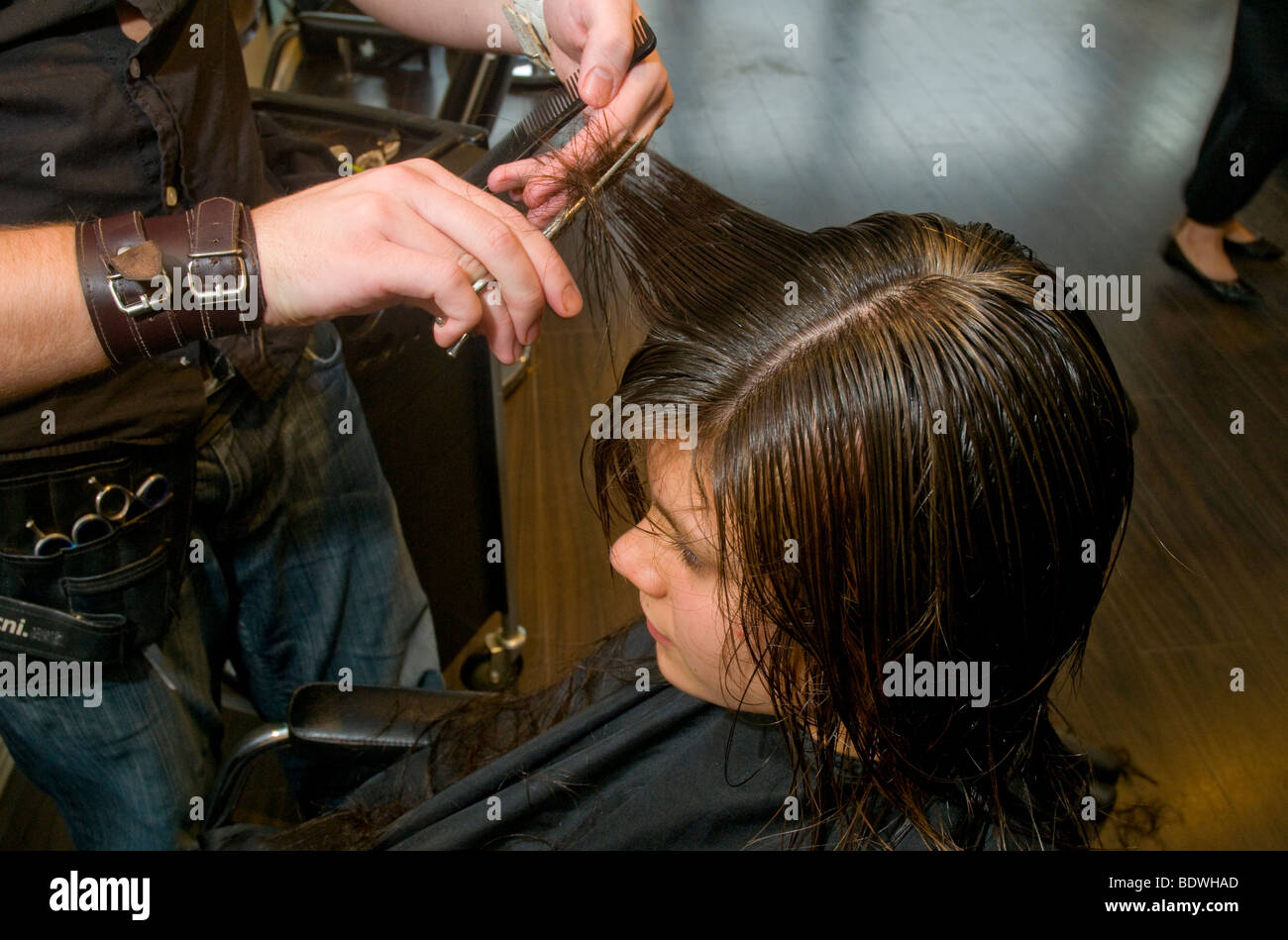 Ein Teenager immer ihr Haar schneiden durch einen Friseur in einen Friseursalon Stockfoto