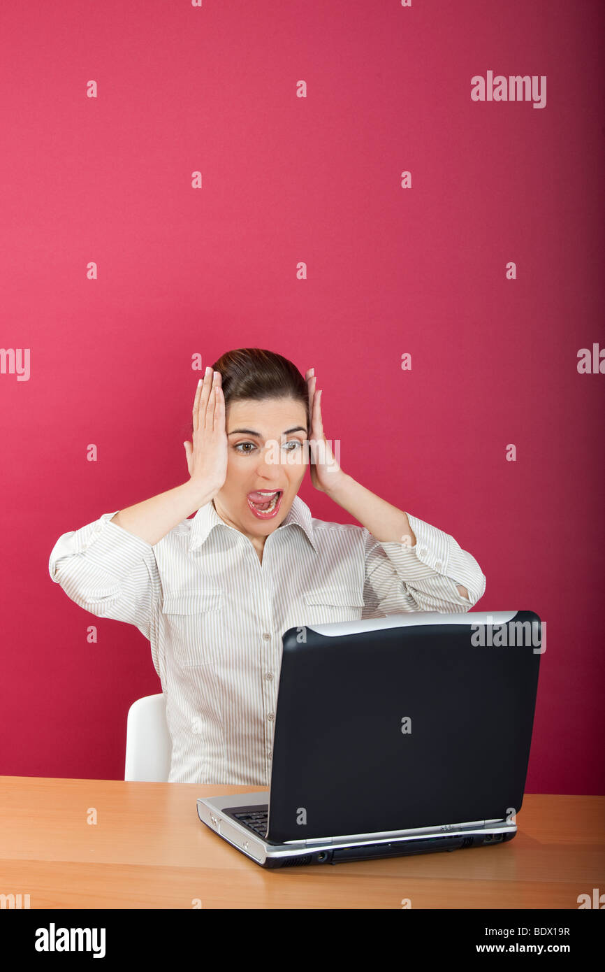 Geschäftsfrau im Büro besorgt mit etwas mit den Händen auf dem Kopf sitzen Stockfoto