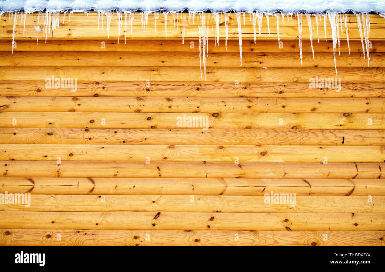Eiszapfen hängen vom Dach Holz Blockwand Stockfoto