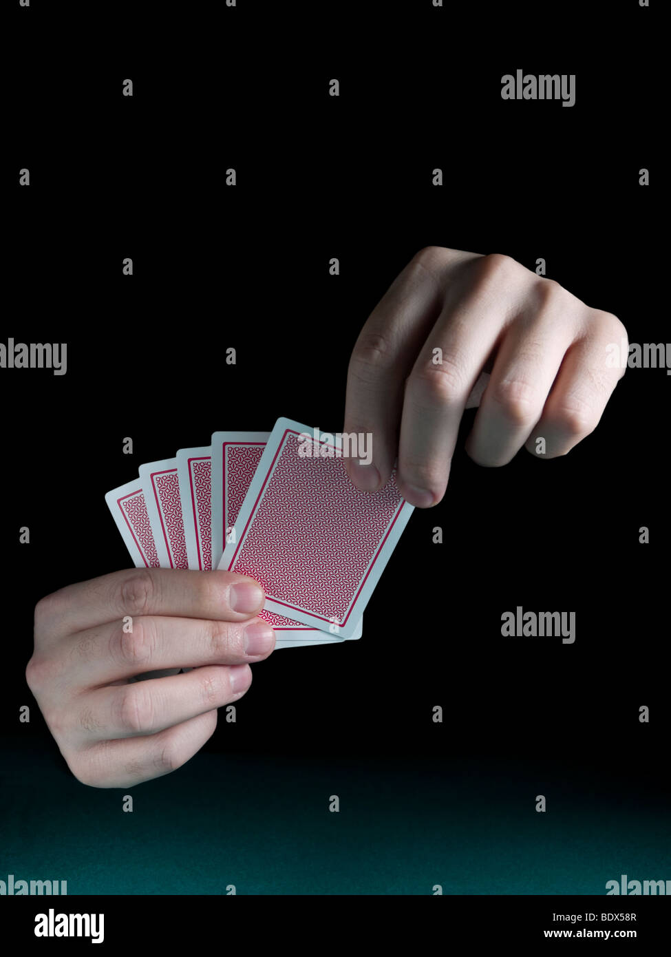 Eines Mannes Hand mit fünf Karten über einen grünen Filz. Stockfoto