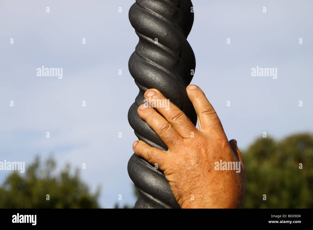 Die Hand eines Mannes stützte sich auf einen Laternenpfahl Spirale Stockfoto