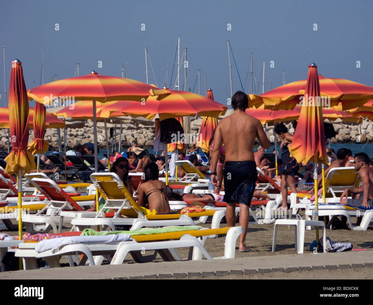 Touristen mit Sonnenschirmen und Sonnenliegen in Larnaca, Zypern. Stockfoto