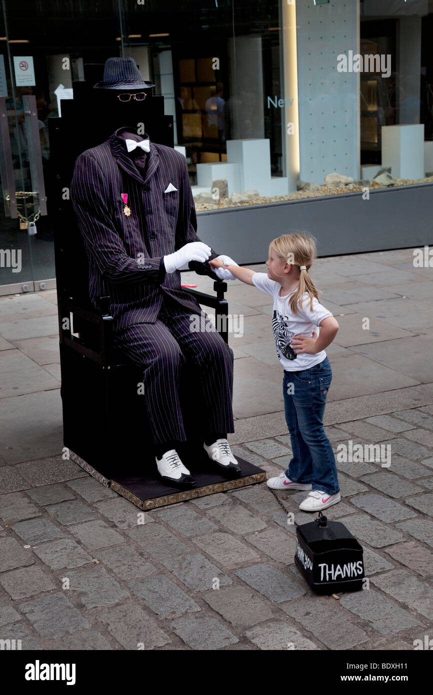 Straßenmusik unsichtbaren Mann nimmt Geld von einem kleinen Mädchen in Covent Garden, London. Dieser Bereich ist voll MIME-Stil Straßenperformance Stockfoto