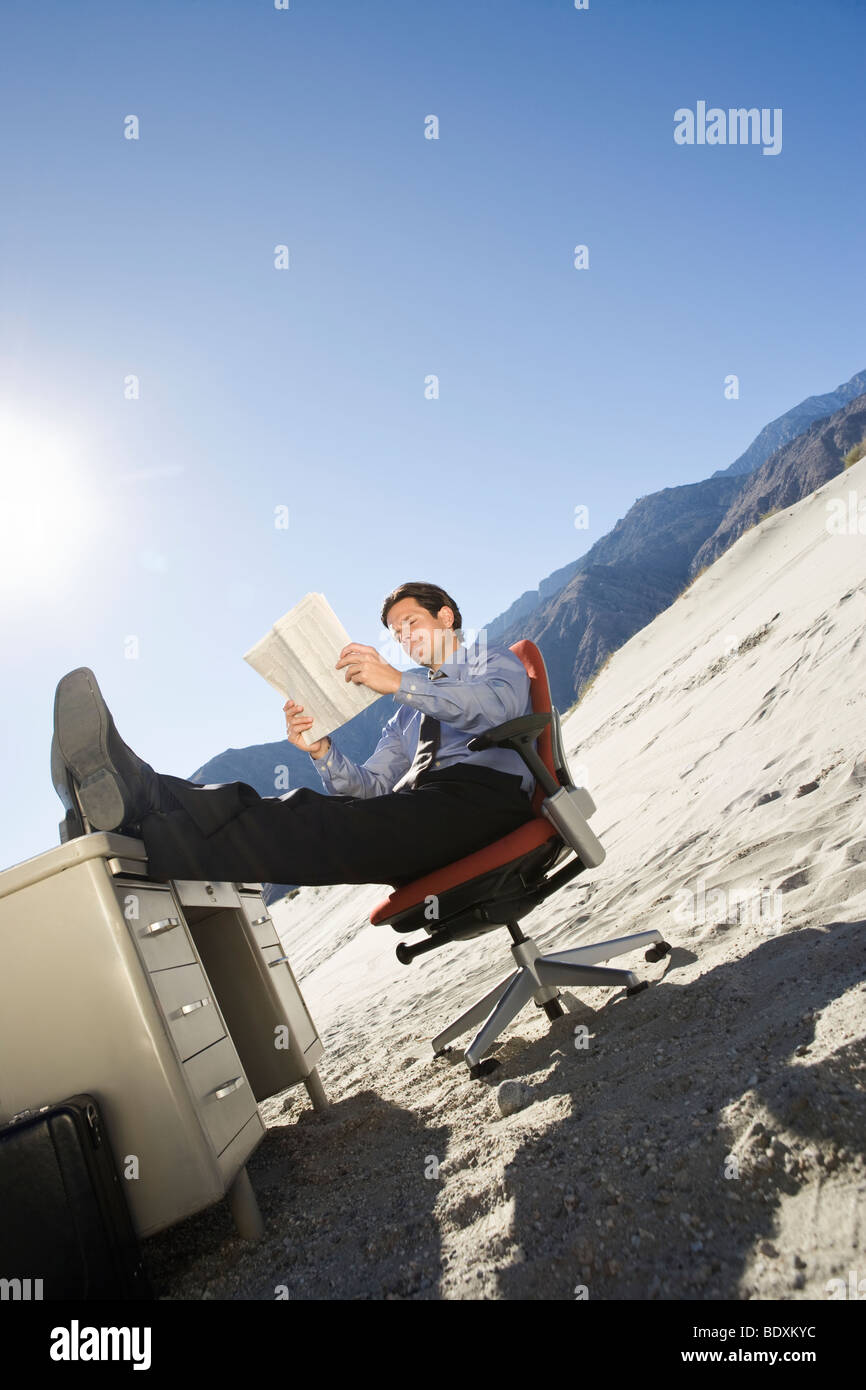 Geschäftsmann am Schreibtisch in der Wüste Stockfoto