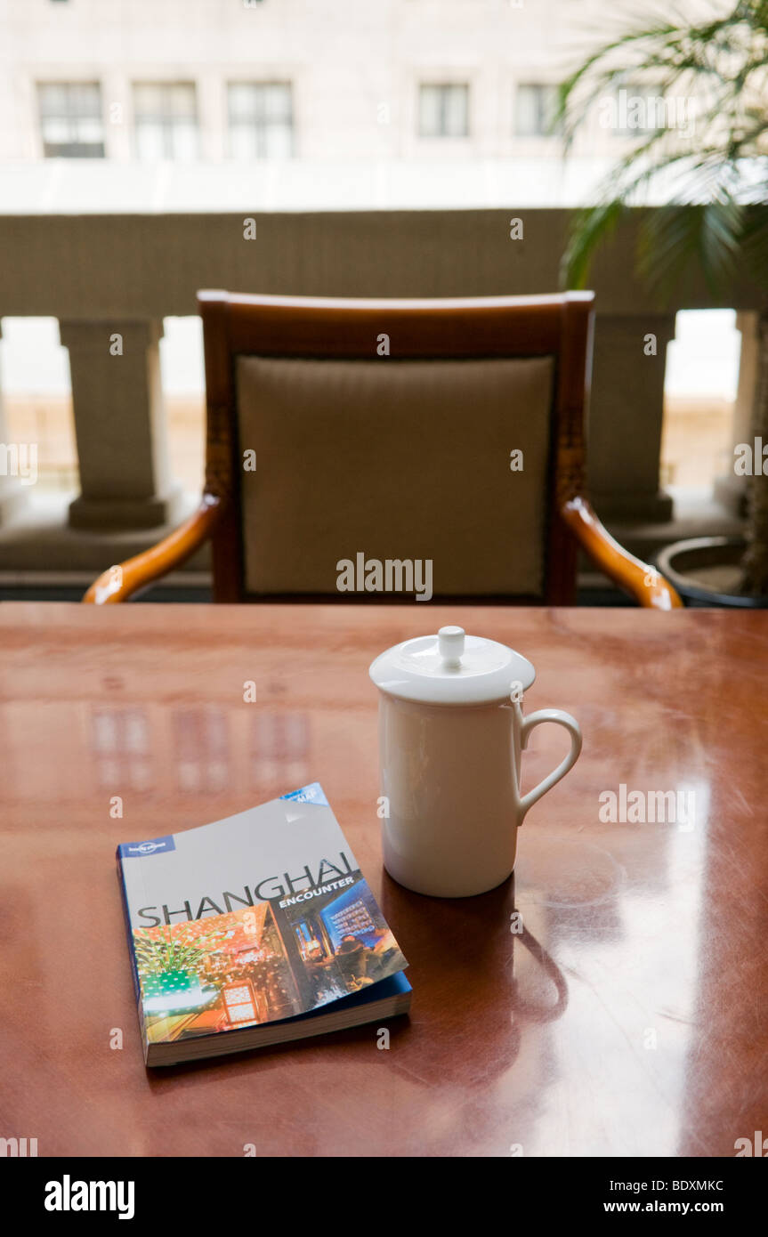 Eine Tasse Chinesischer Jasmintee und einen Führer buchen im überdachten Wasserglas in einem Café in Shanghai China Stockfoto